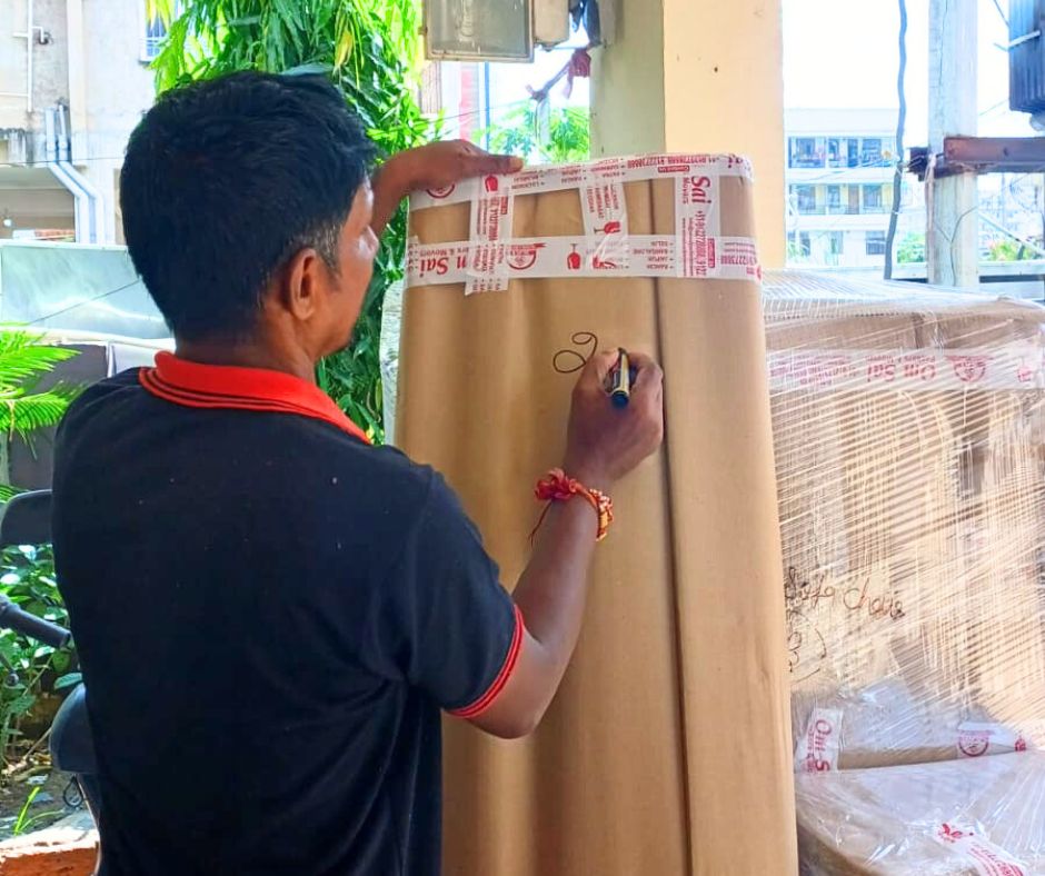 A worker from Om Sai Packers and Movers in Boring Road carefully labeling a packed household item for safe relocation.